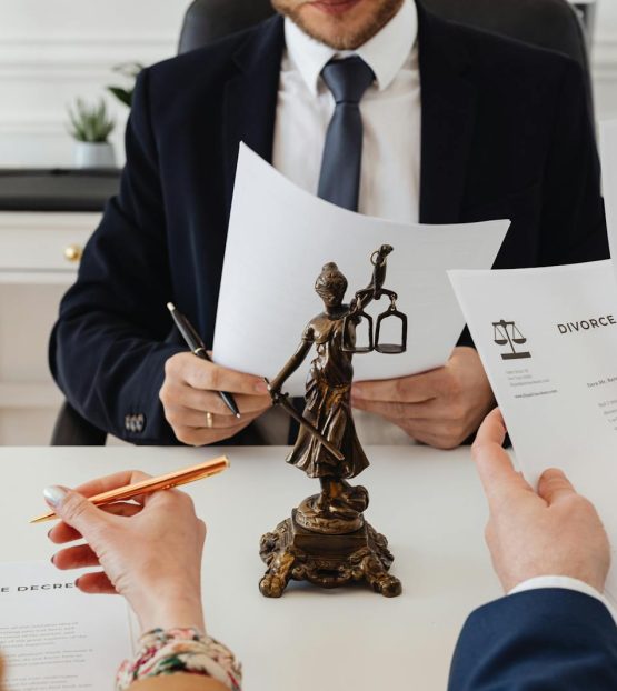 Legal professionals reviewing divorce documents in a law office with a Lady Justice statue. {{brizy_dc_image_alt imageSrc=